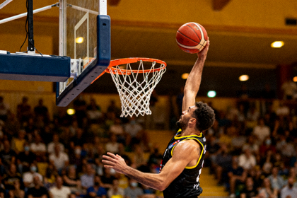 室内篮球比赛现场，球员在篮下完成上篮动作